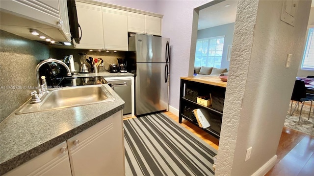 kitchen featuring backsplash, light hardwood / wood-style floors, sink, and stainless steel appliances