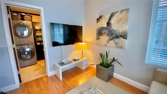 laundry room featuring light hardwood / wood-style flooring and stacked washing maching and dryer