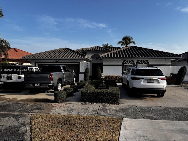 view of front of property with stucco siding, an attached garage, a tiled roof, and concrete driveway