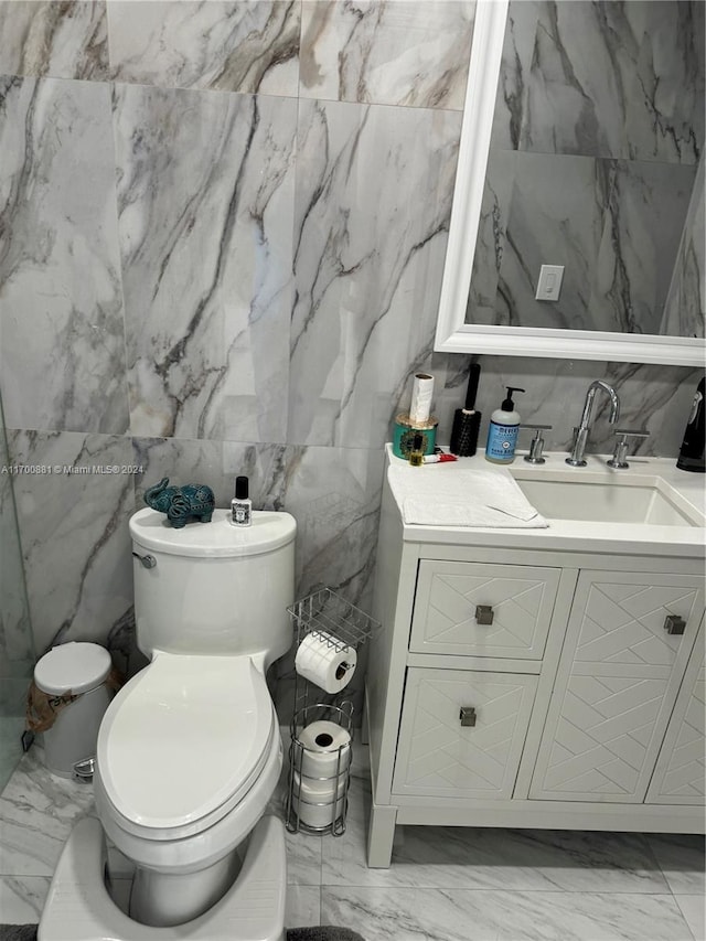 bathroom featuring vanity, tile walls, and toilet