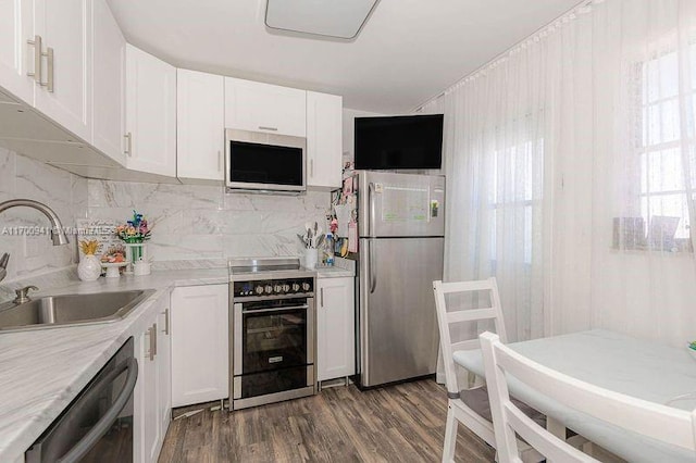 kitchen featuring appliances with stainless steel finishes, dark hardwood / wood-style flooring, backsplash, sink, and white cabinetry