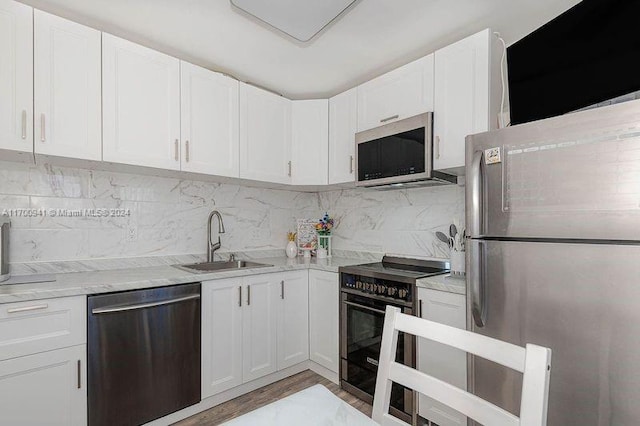 kitchen featuring white cabinets, sink, decorative backsplash, appliances with stainless steel finishes, and light hardwood / wood-style floors