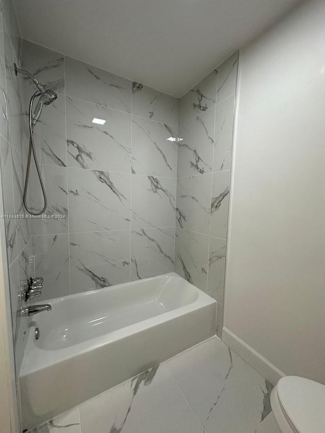 bathroom with toilet and tiled shower / bath