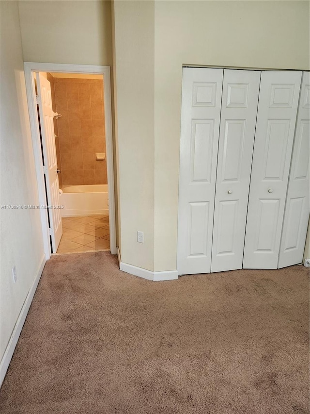 unfurnished bedroom with a closet, ensuite bathroom, and light colored carpet