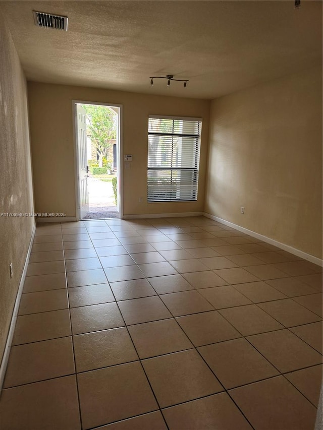 spare room with a textured ceiling and tile patterned floors