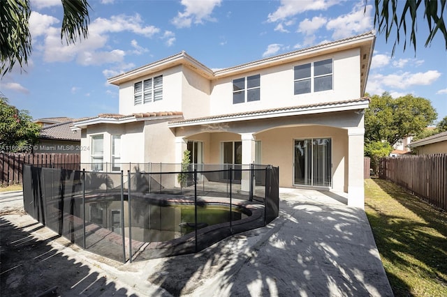 rear view of house with a fenced in pool and a patio