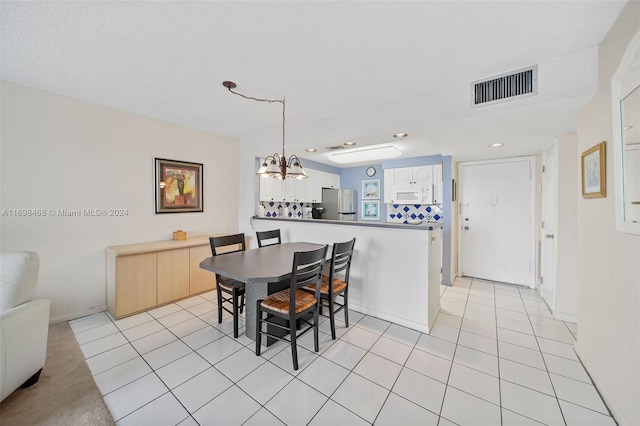 tiled dining area with a textured ceiling and a notable chandelier