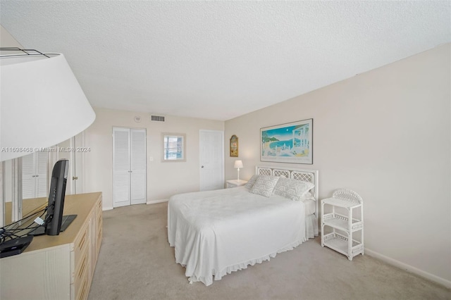 bedroom featuring a textured ceiling and light carpet