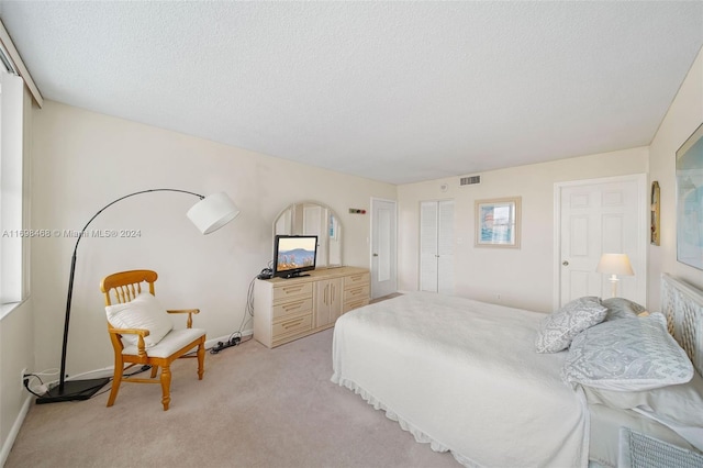 bedroom featuring light colored carpet and a textured ceiling