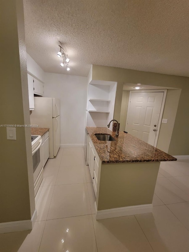 kitchen with white appliances, dark stone counters, white cabinets, sink, and a textured ceiling