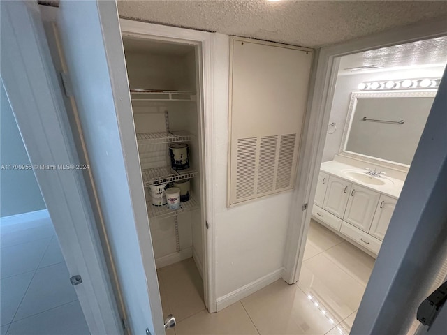 bathroom featuring tile patterned flooring, vanity, and a textured ceiling