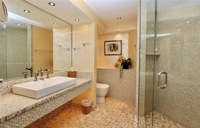 bathroom with tile patterned floors, toilet, an enclosed shower, sink, and tile walls