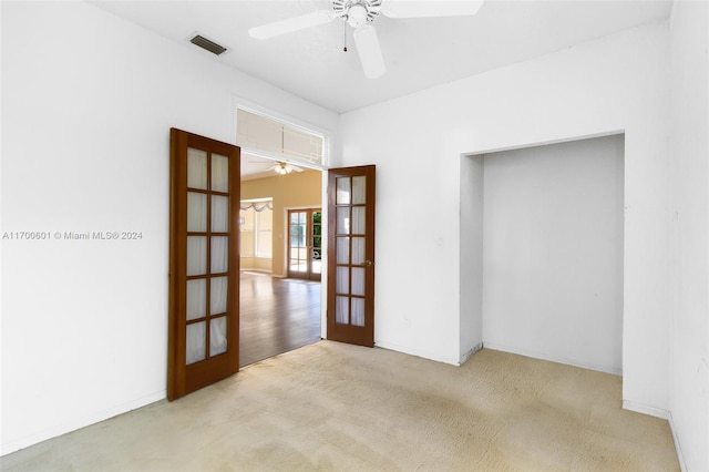 empty room with light carpet, french doors, and ceiling fan