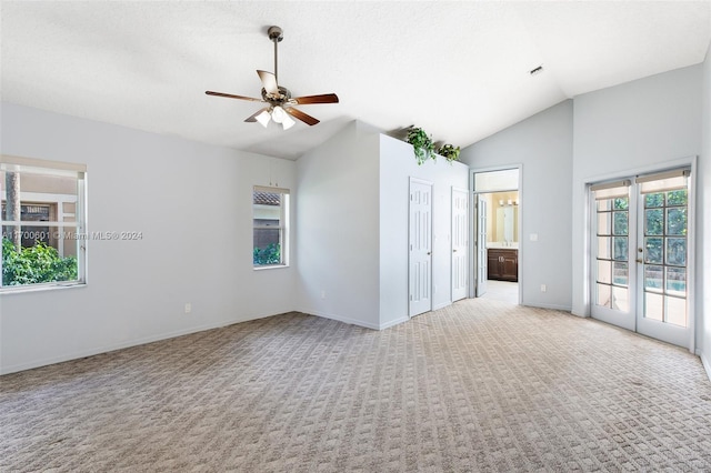 carpeted spare room with french doors, vaulted ceiling, and ceiling fan