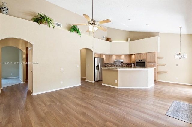 kitchen featuring appliances with stainless steel finishes, light wood-type flooring, light brown cabinetry, ceiling fan, and high vaulted ceiling