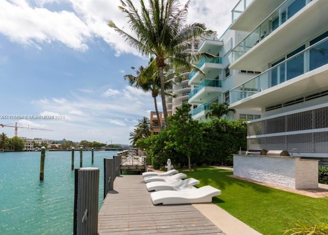 view of dock with a yard, a water view, and an outdoor kitchen