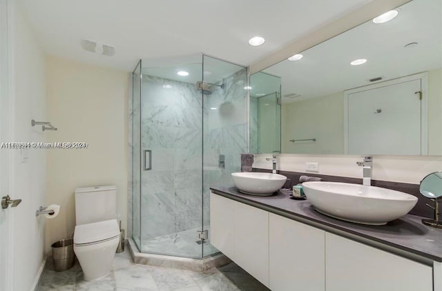 bathroom featuring a shower with door, vanity, and toilet