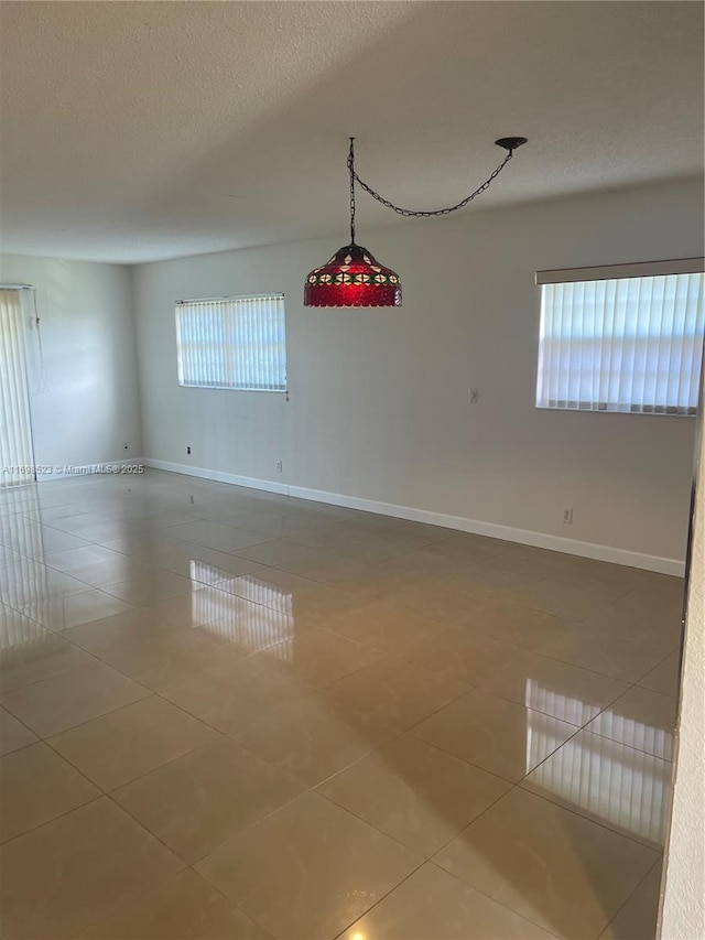 unfurnished room featuring plenty of natural light, tile patterned floors, and a textured ceiling