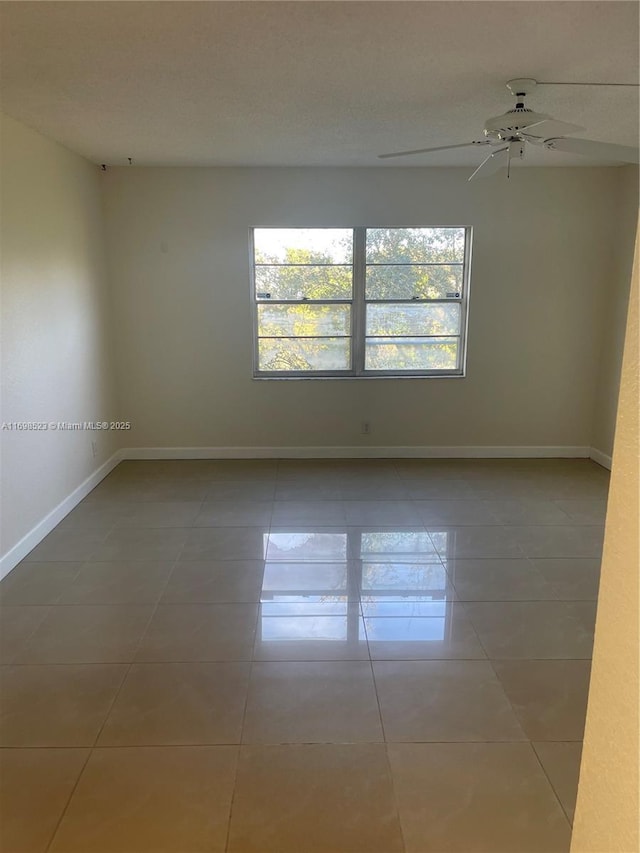 empty room with ceiling fan and tile patterned floors