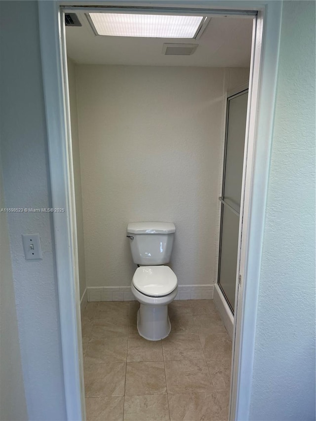 bathroom featuring tile patterned flooring, an enclosed shower, and toilet