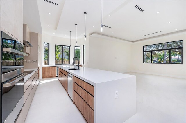 kitchen with a spacious island, sink, ceiling fan, decorative light fixtures, and stainless steel appliances