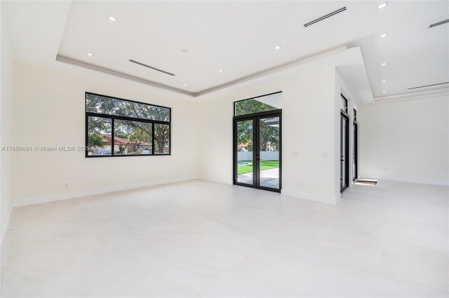 spare room with a raised ceiling, french doors, and a healthy amount of sunlight