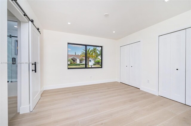 unfurnished room with a barn door and light hardwood / wood-style flooring