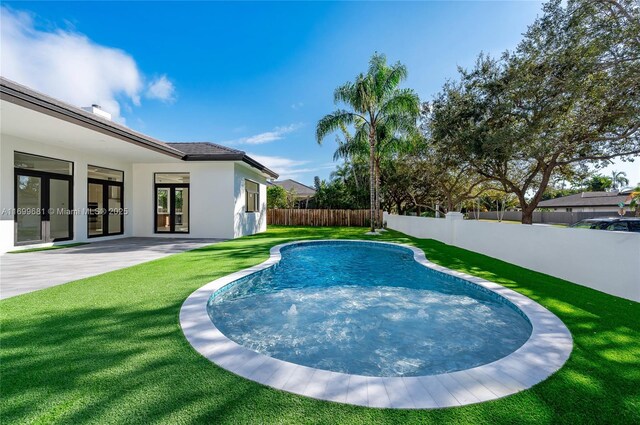 view of swimming pool featuring a yard, a patio area, and french doors