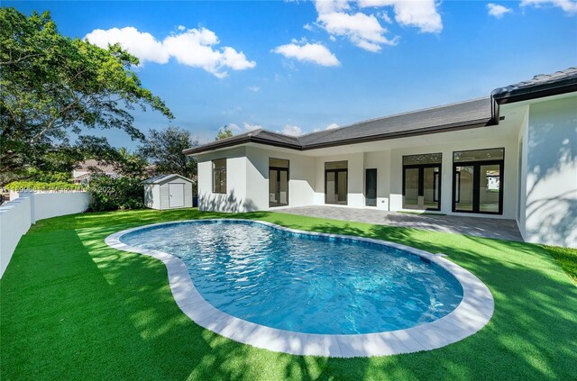 rear view of property featuring a lawn, a patio, and a storage unit