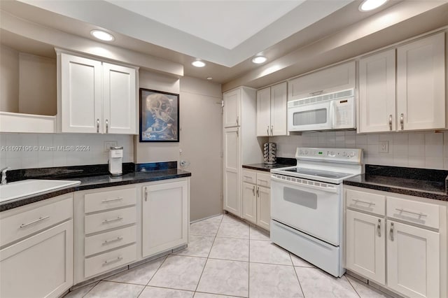 kitchen with white appliances, backsplash, sink, light tile patterned floors, and white cabinetry