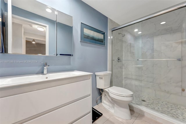 bathroom with tile patterned flooring, vanity, a shower with shower door, and toilet