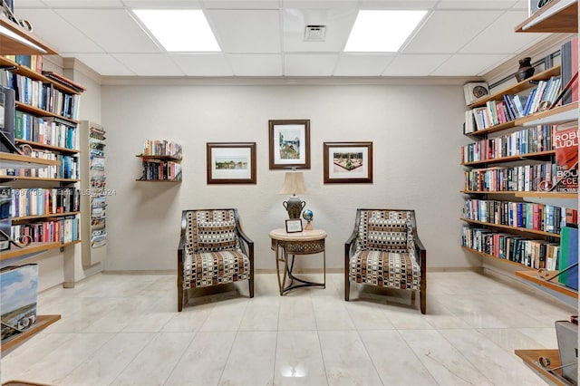 living area featuring light tile patterned floors and a paneled ceiling