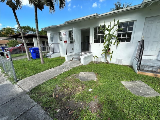 view of front of home featuring a front lawn, fence, and stucco siding