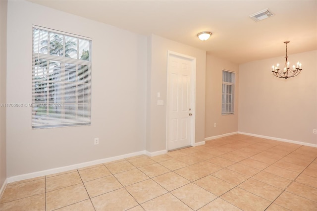 unfurnished room featuring light tile patterned floors and a notable chandelier