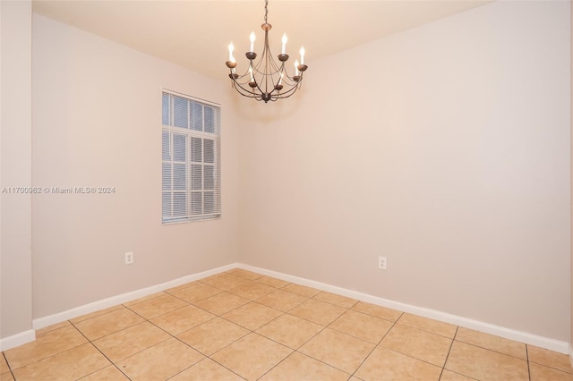 tiled empty room featuring an inviting chandelier