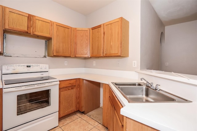 kitchen with white range oven, light tile patterned floors, and sink