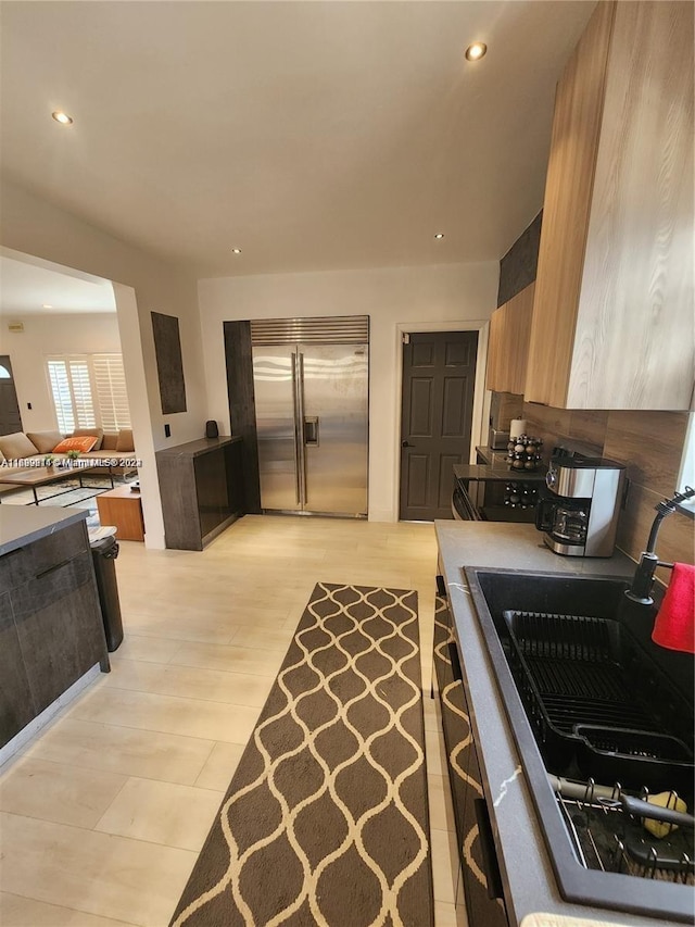 kitchen with stainless steel built in refrigerator, light wood-type flooring, and sink