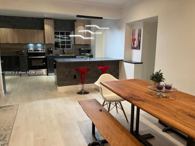 kitchen with sink, tasteful backsplash, a kitchen breakfast bar, stove, and light hardwood / wood-style floors