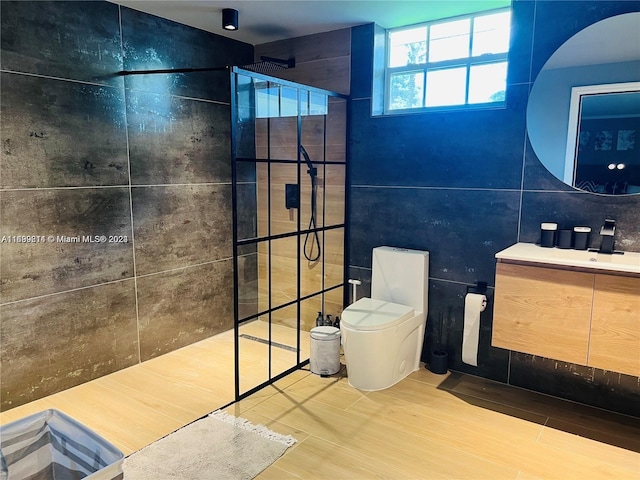 bathroom with toilet, tiled shower, vanity, tile walls, and hardwood / wood-style flooring