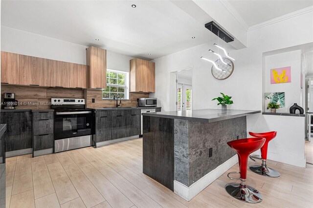 13751 NE 1st Ave, Miami, FL 33161 - kitchen with appliances with stainless steel finishes, dark countertops, light wood-style flooring, crown molding, and a kitchen breakfast bar