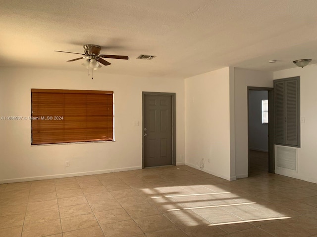 spare room with light tile patterned floors, a textured ceiling, and ceiling fan