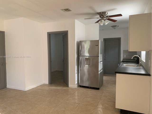 kitchen with stainless steel fridge, tasteful backsplash, ceiling fan, sink, and light tile patterned floors