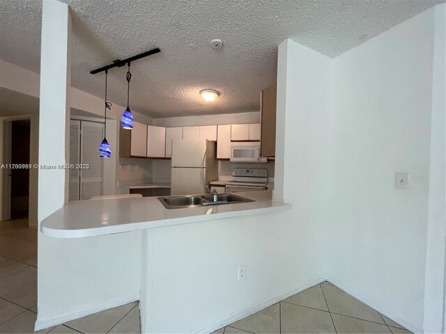 4015 W Mcnab Rd Unit D101, Pompano Beach, FL 33069 - kitchen featuring white appliances, light tile patterned flooring, light countertops, a peninsula, and a textured ceiling