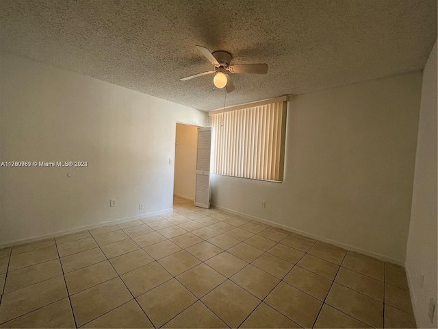 empty room with a textured ceiling, ceiling fan, and light tile patterned flooring