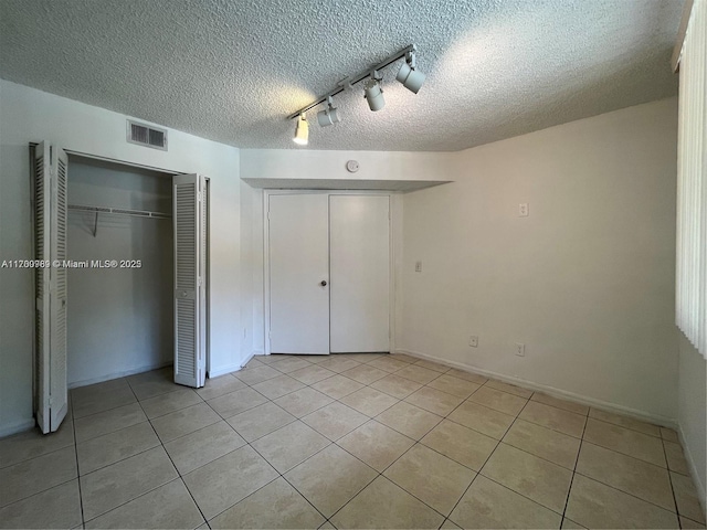 4015 W Mcnab Rd Unit D101, Pompano Beach, FL 33069 - unfurnished bedroom featuring light tile patterned flooring, a textured ceiling, rail lighting, and a closet