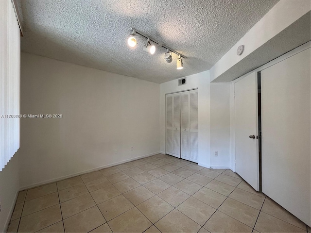 4015 W Mcnab Rd Unit D101, Pompano Beach, FL 33069 - unfurnished bedroom featuring light tile patterned flooring, a textured ceiling, rail lighting, and a closet