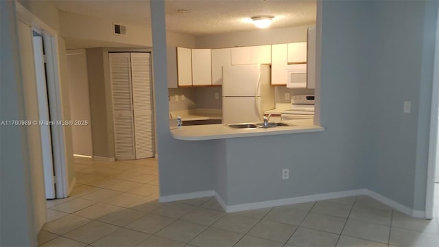 4015 W Mcnab Rd Unit D101, Pompano Beach, FL 33069 - kitchen featuring white appliances, light countertops, white cabinets, light tile patterned floors, and a peninsula