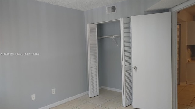 4015 W Mcnab Rd Unit D101, Pompano Beach, FL 33069 - unfurnished bedroom featuring light tile patterned floors, a closet, and a textured ceiling