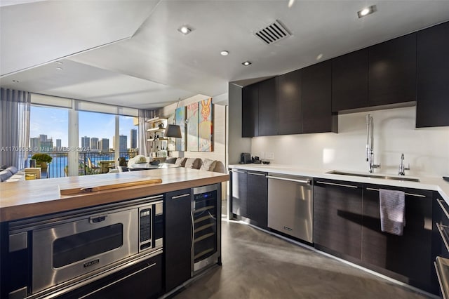 kitchen with wine cooler, a wall of windows, sink, and appliances with stainless steel finishes