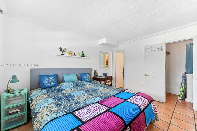 tiled bedroom featuring a textured ceiling and crown molding